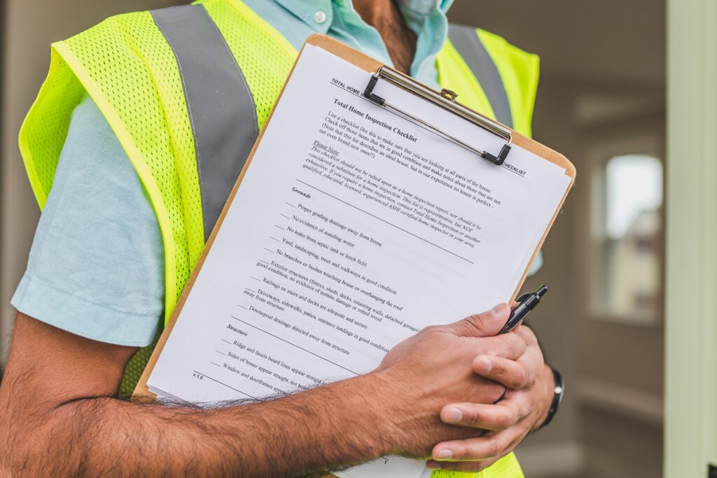 man wearing a yellow safety vest with silver reflective stripes holding a brown clipboard with a NYSEG rebate