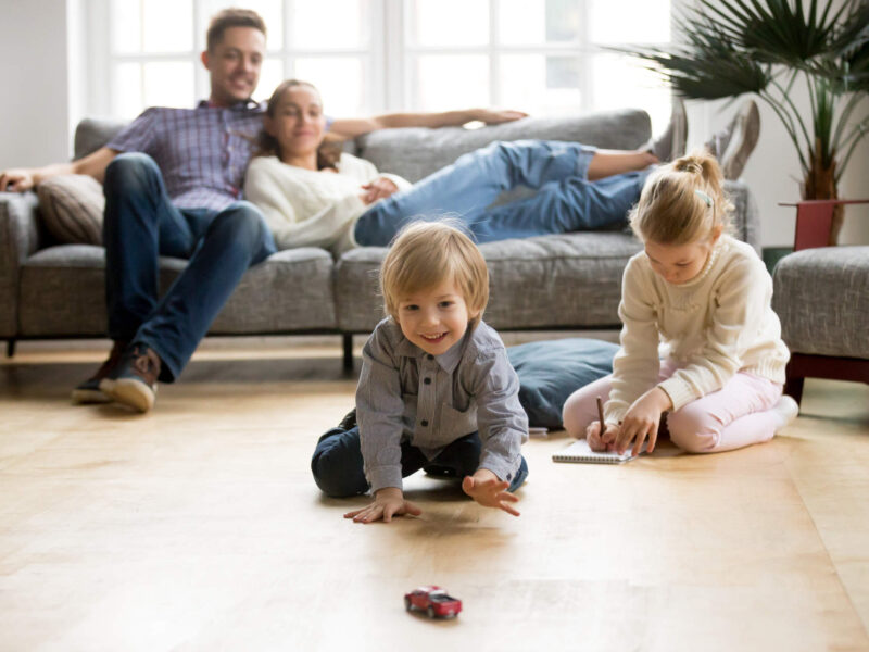 a family of four enjoying time together in a living room with a comfortable temperature after installing a heat pump