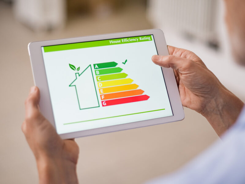 Hand holding digital tablet and looking at house efficiency rating. Detail of house efficiency rating on digital tablet screen. Concept of ecological and bio energetic house. Energy class.